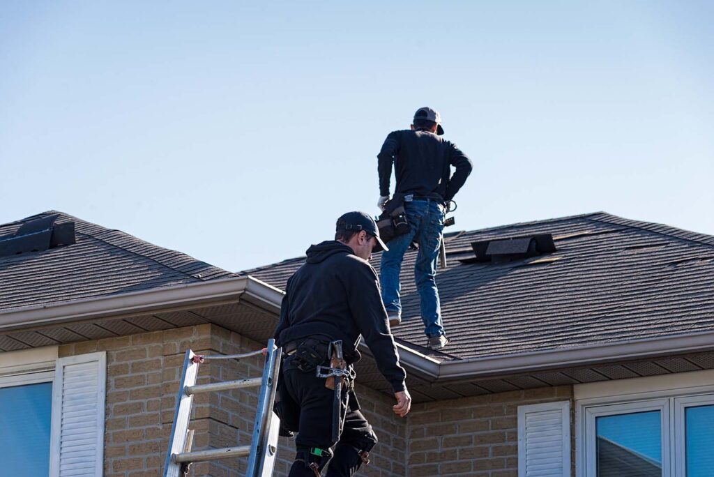 Two roofers inspecting a damaged metal roof in san antonio