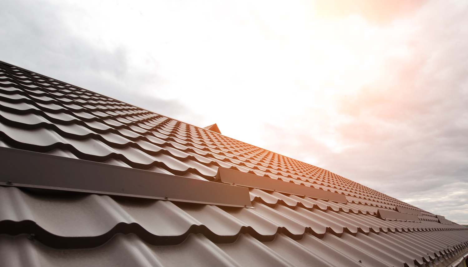 sun sets behind a copper metal roof