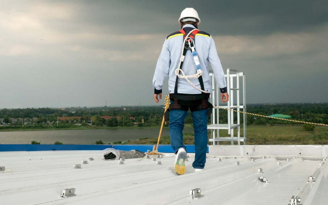 contractor in safety gear walking across a metal roof during an inspection