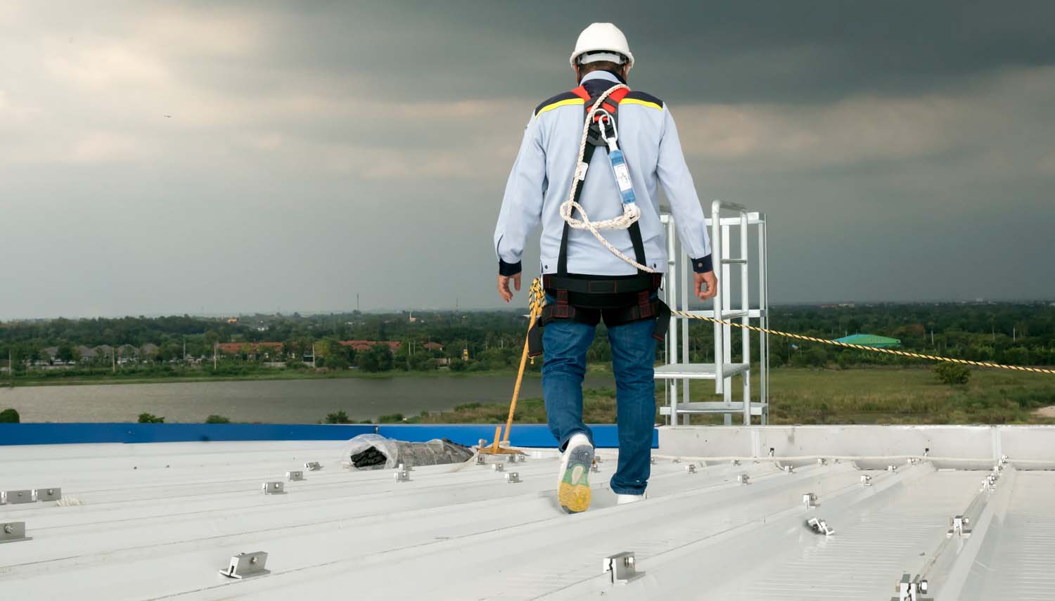 contractor in safety gear walking across a san antonio metal roof during an inspection
