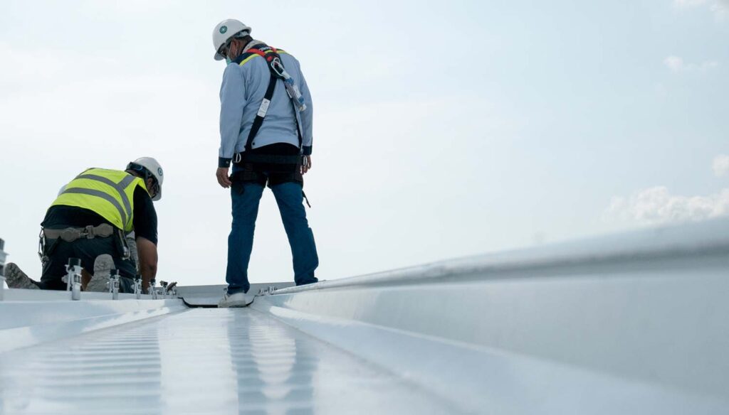 contractors on a roof performing a metal panel roof seams inspections in san antonio