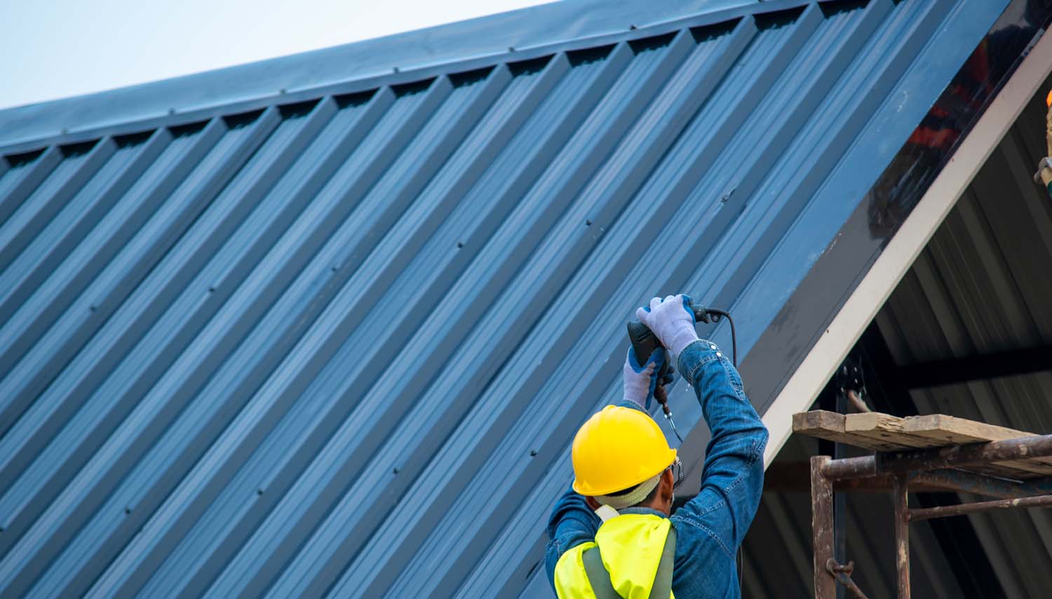 contractor in yellow safety cap fixing metal roof