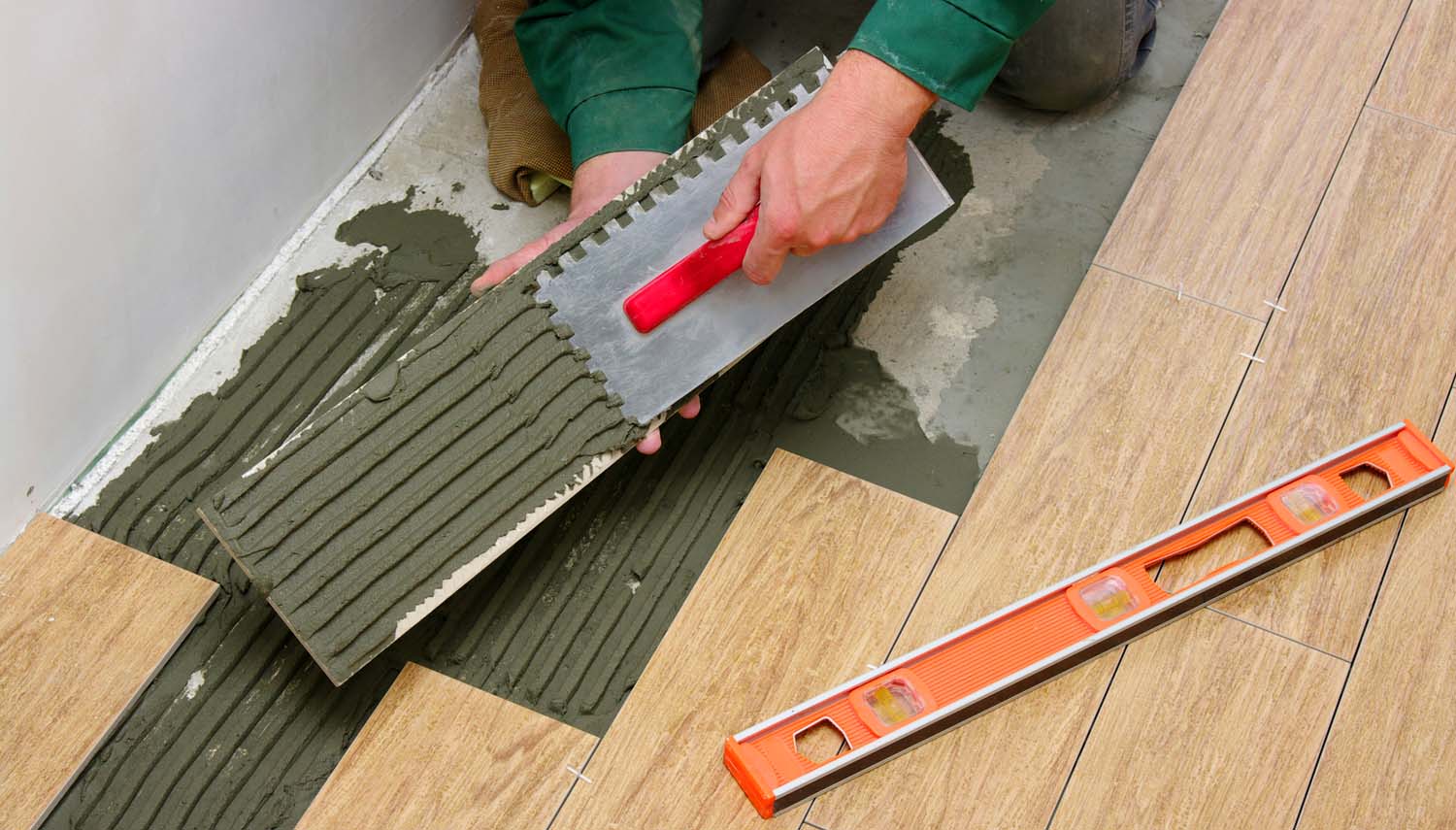 close up of a contractor on one knee repairing sections of a laminate flooring in San Antonio