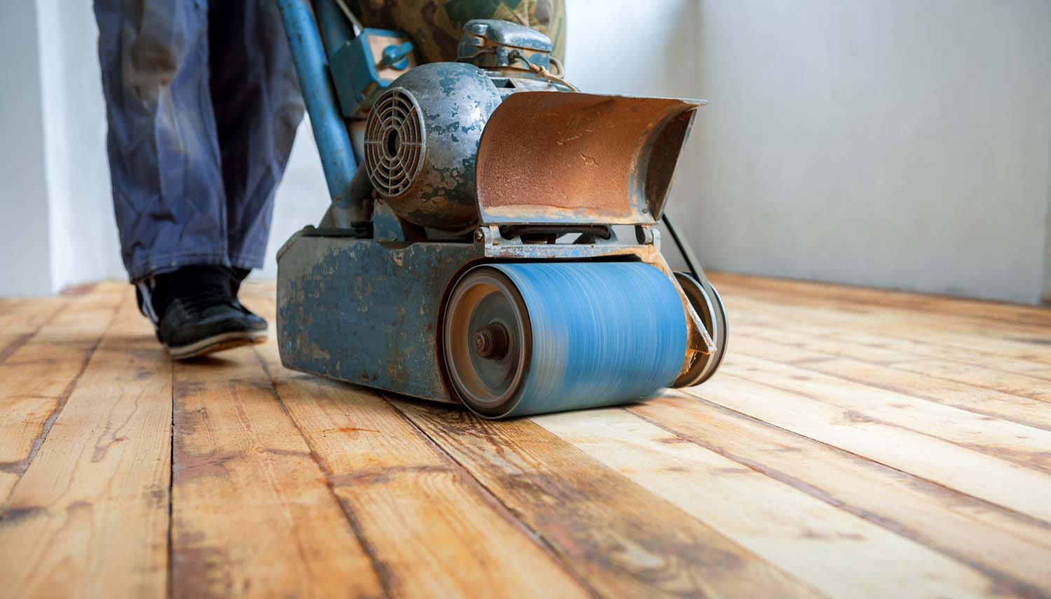 tight view of a contractor with a belt sander sanding a floor for a homeowner in san antonio