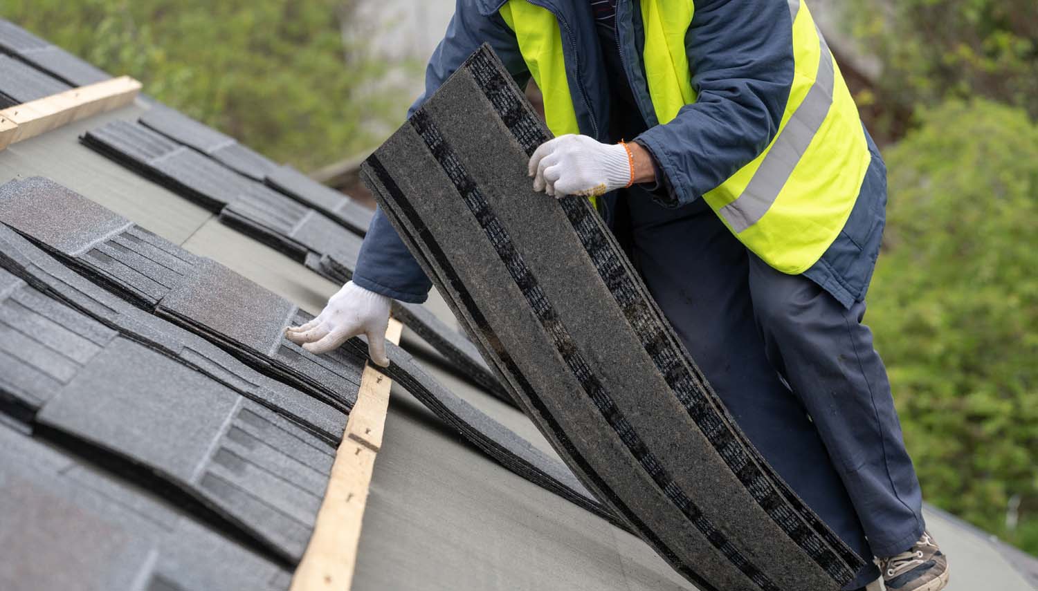 roofing contractor replacing sections of asphalt shingles on a roof after a storm in san antonio has damaged the roof