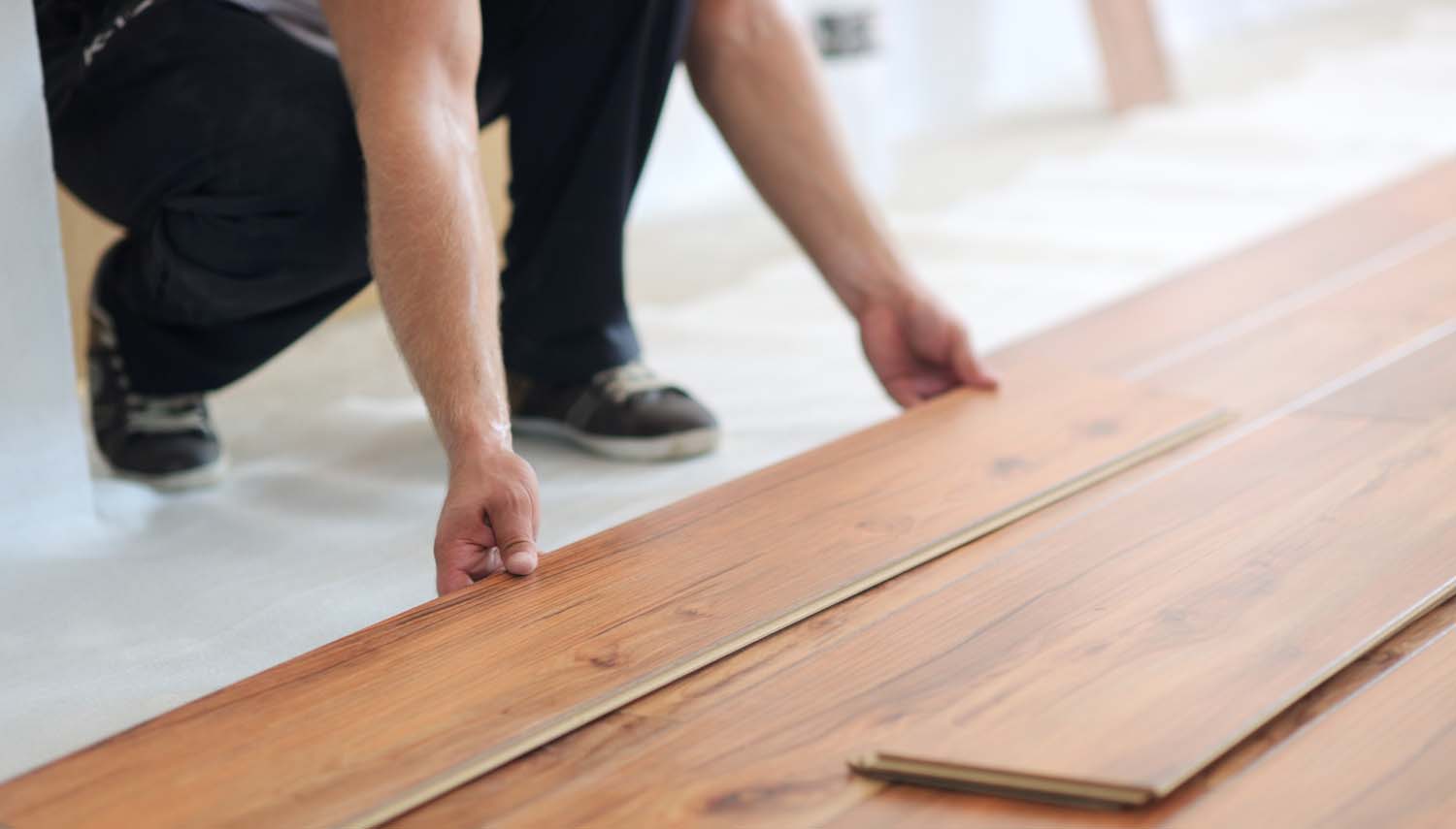 contractor kneeling while installing laminate flooring in a san antonio home