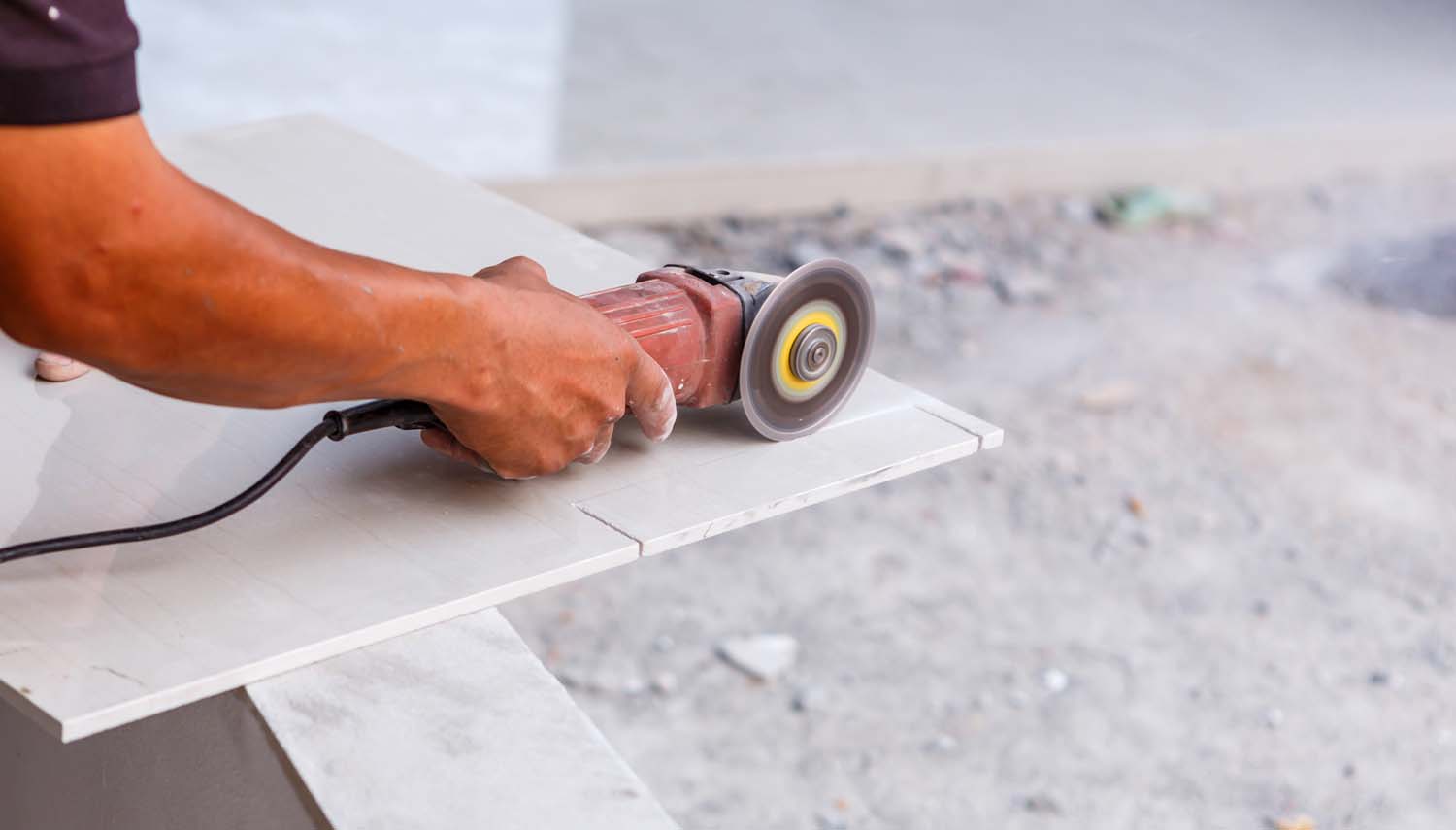 contractor with skill saw cutting ceramic floor tile close up