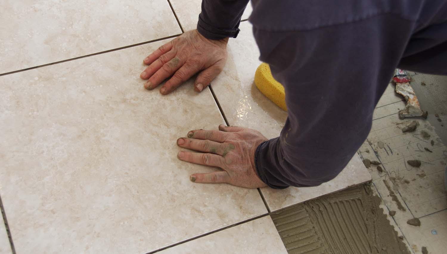 contractor with a trowel is installing floor tiles in san antonio home