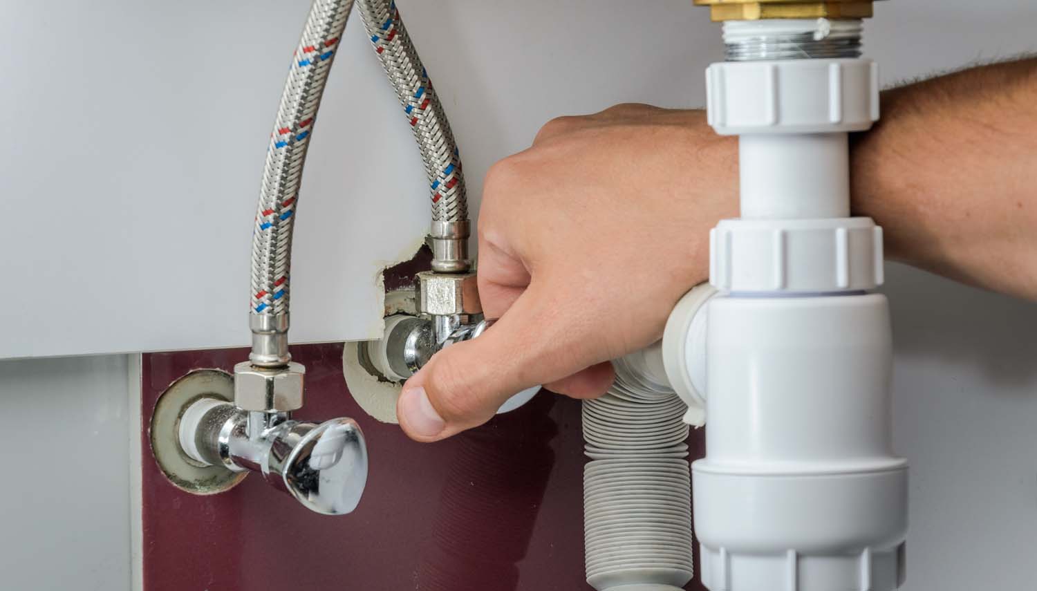 contractor is fixing a kitchen water fixtures below the sink in a san antonio home